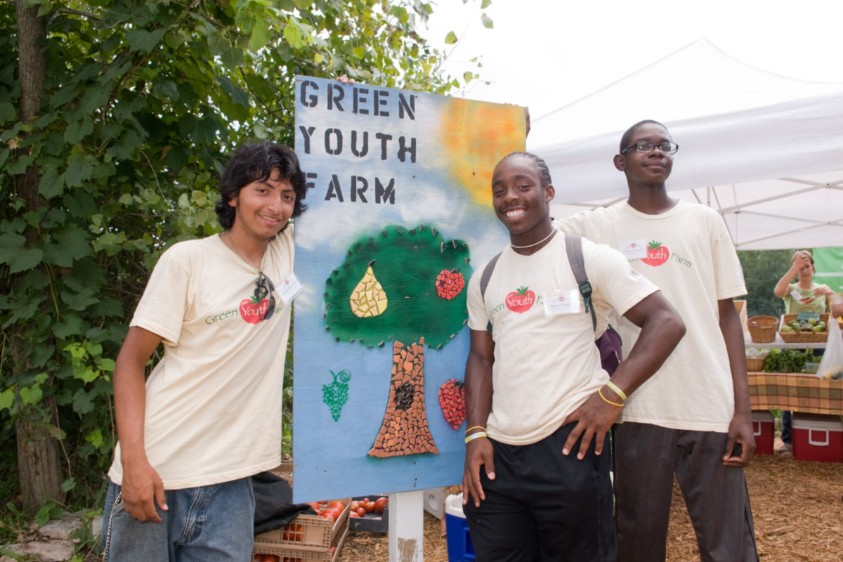 Teens with "Green Youth Farm" sign